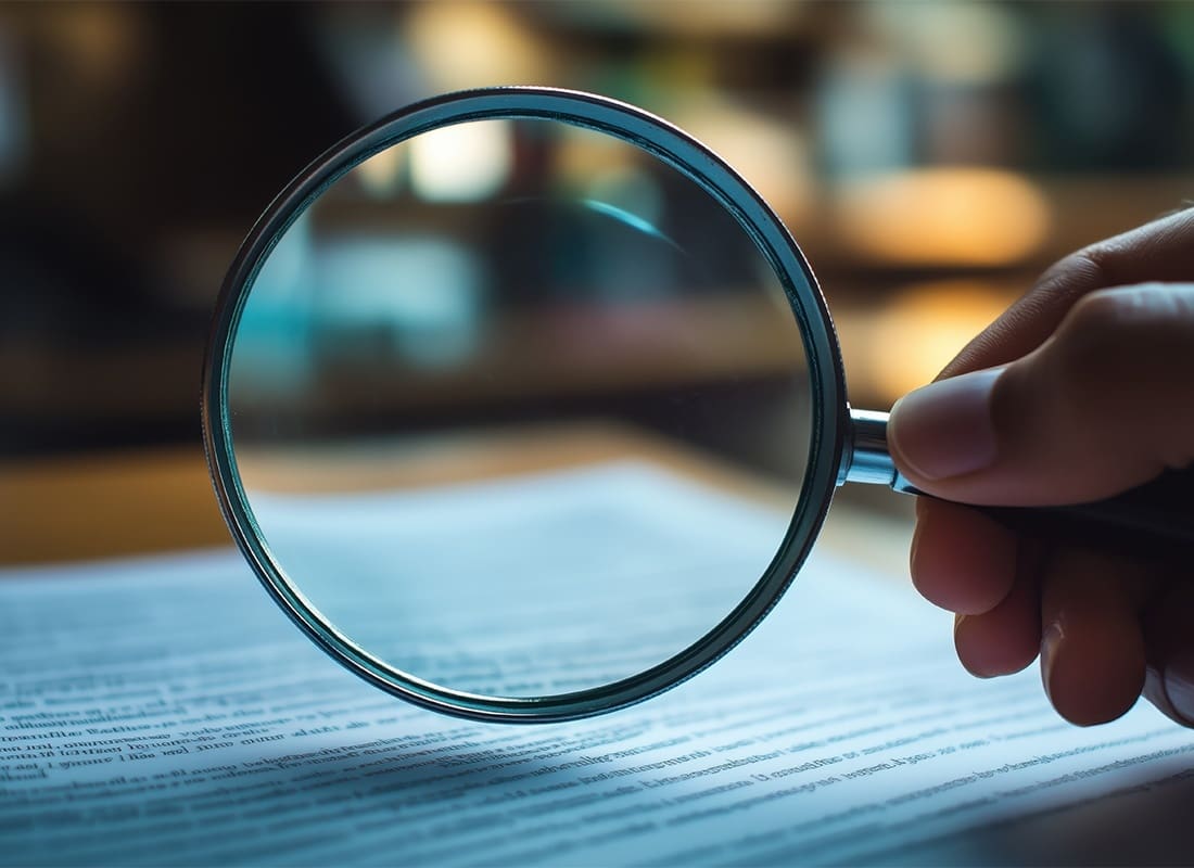 Insurance-Glossary-Person-Holding-a-Magnifying-Glass-Over-Documents-on-a-Table