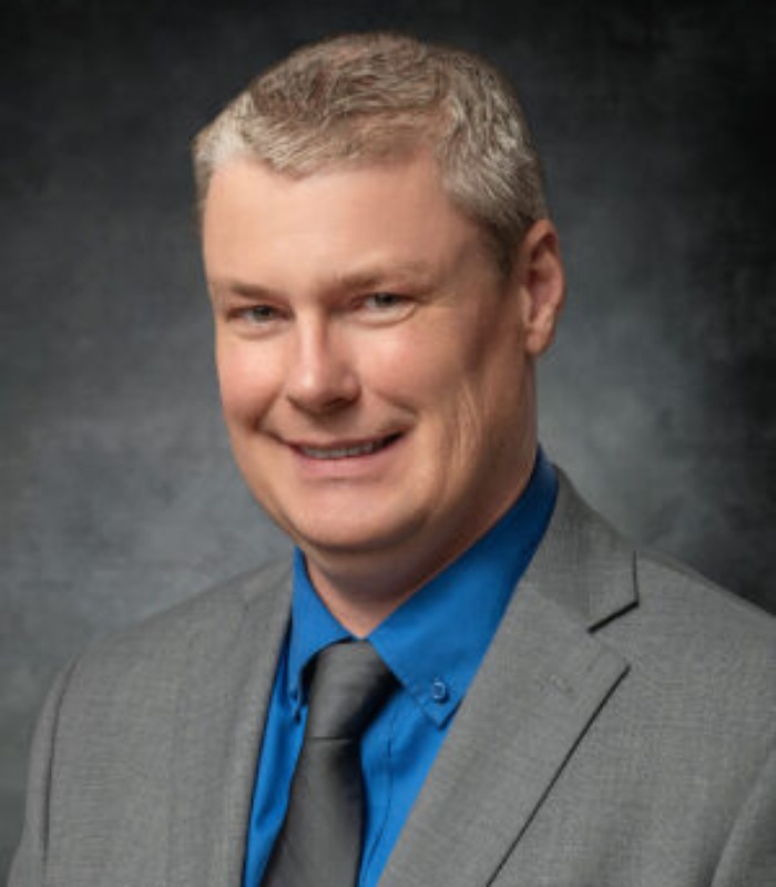 Meet Our Team - Professional and Welcoming Group at a Conference Table Faces the Camera, Team Leader Sitting on the Table with Arms Folded